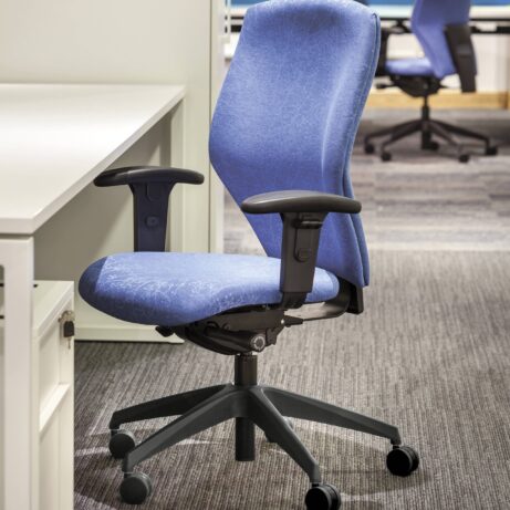 BLAST Task Chair in blue fabric with curved backrest, adjustable height, and armrests, set in a modern office environment.