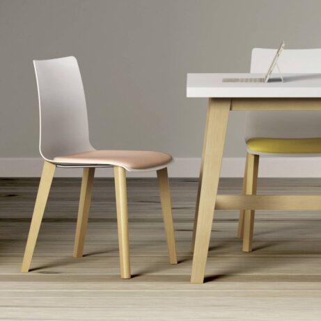 FJORD Chair with white polypropylene shell and wooden legs, featuring a beige seat, beside a table in a modern setting.