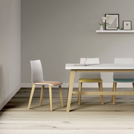 FJORD Chair with a polypropylene shell and wooden legs, featuring a light pink seat in a modern café setting.