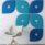 Hush Wall Mounted Acoustic Panels in blue and teal, featuring timber centers, arranged on a white wall with a chair in front.