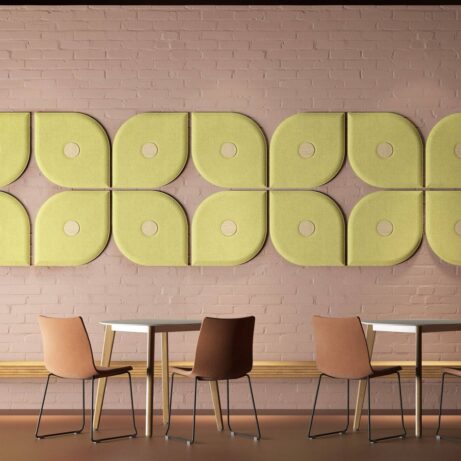 Hush Wall Mounted Acoustic Panels in green and beige, arranged on a pink wall above modern chairs and tables.