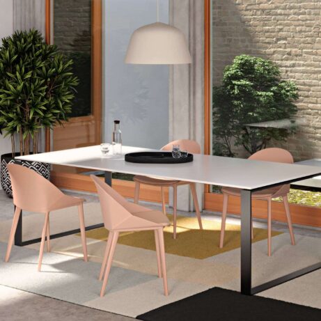 Papillon Meeting & Café Chair in pink, featuring a modern design with a compact footprint beside a stylish table in a bright space.