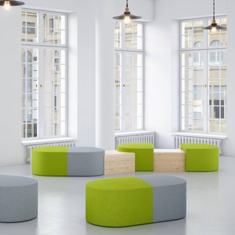 Modular PILL seating system in green and gray fabric with integrated tables, arranged for collaborative spaces in a bright room.